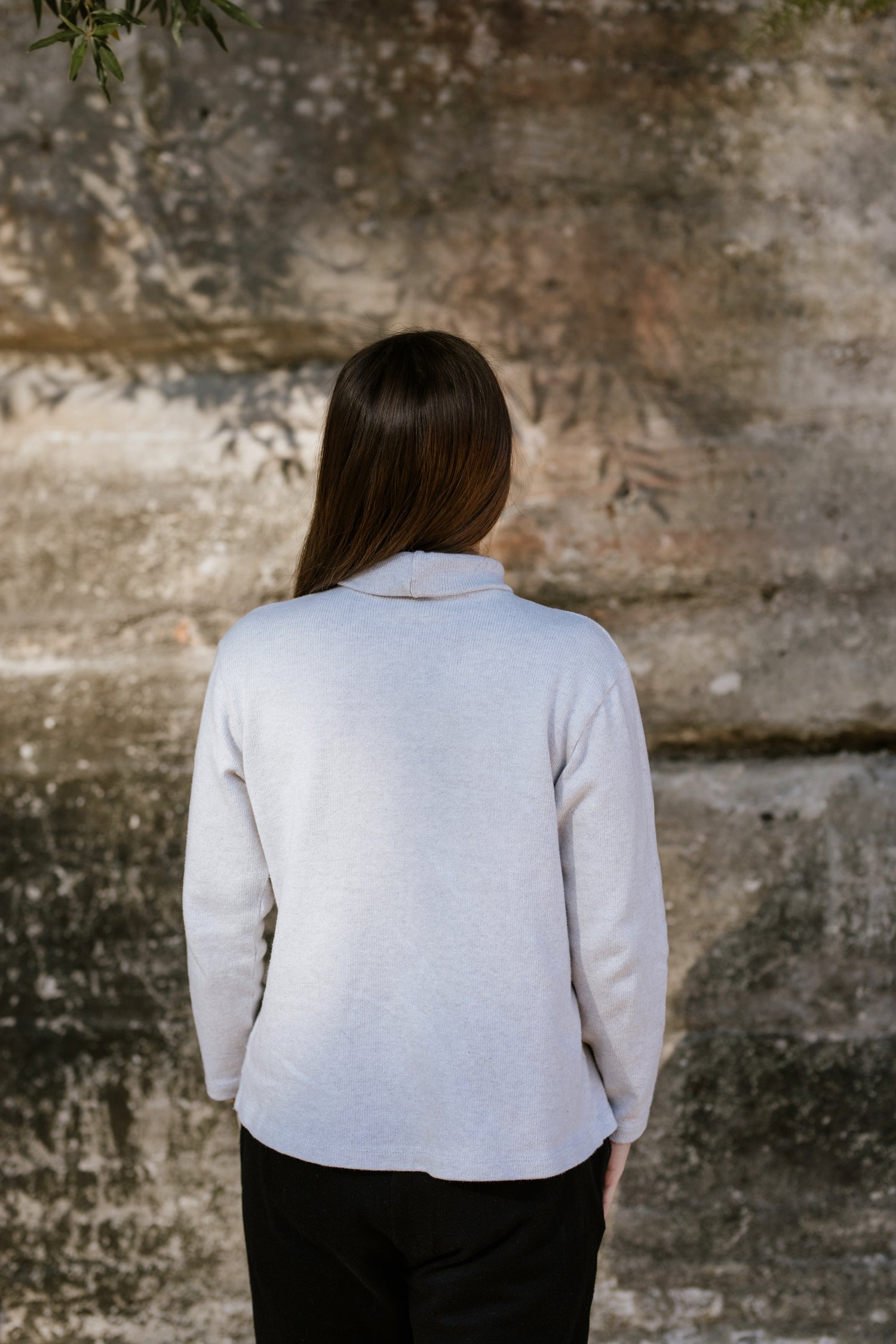 Short, petite woman wearing a turtleneck knit jumper/sweater.